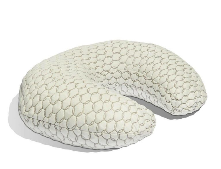 A light-colored U-shaped nursing pillow with a honeycomb-patterned cover is shown. The pillow's texture and design suggest it is intended for neck or travel use. The image background is plain white.