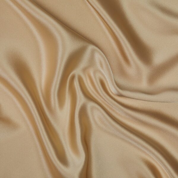 A close-up image of a Silk Pillowcase. The material has a smooth, shiny surface and exhibits soft, flowing folds that create a sense of gentle movement and luxury. The rich, shimmering texture highlights the pillowcase's elegant and sophisticated appearance.