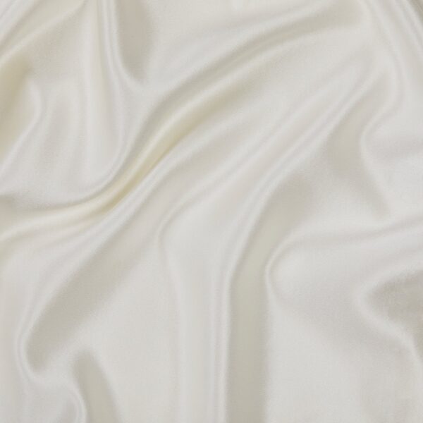 A close-up of the smooth, white fabric of our Silk Pillowcase, showcasing its soft, elegant folds and ripples that create a glossy and luxurious texture.