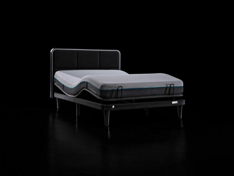 The Ergo Sportive Adjustable Smart Bed, featuring a sleek black frame, is showcased against a black background. The mattress is displayed in an elevated position at the head, highlighting its adjustable capabilities. This modern bed boasts a minimalist design with a padded headboard.