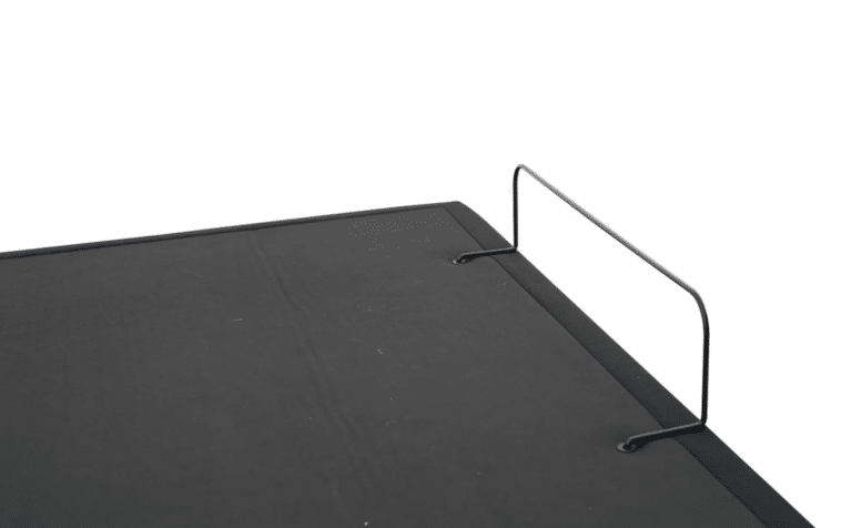 A close-up image of the black tabletop surface of the DUETTO Split Top Adjustable Base, featuring two metal wire brackets extending vertically from the edge for support or securing objects, set against a white background.