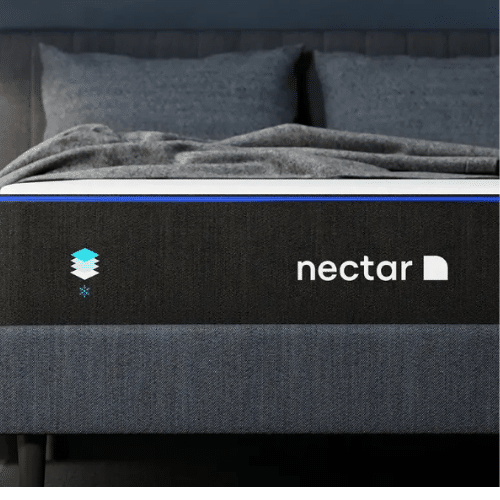 Close-up of a neatly made bed with a black mattress. The side of the mattress has the branding "nectar" with a blue and white logo next to it. The bed has dark gray blankets and pillows on it, and the headboard is upholstered in a similar dark gray fabric.