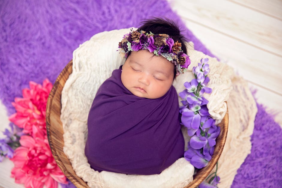 a baby sleeping in a basket with purple flowers