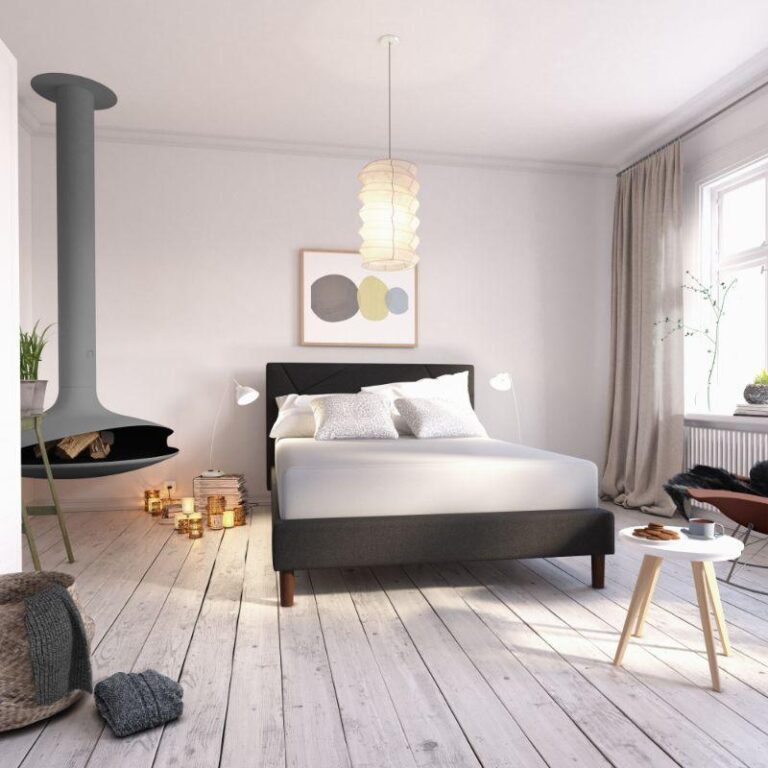 A minimalist bedroom with light wood floors, a gray modern bed, and white bedding. A unique suspended black fireplace hangs to the left, surrounded by candles. A pendant light and abstract art add style, while large windows with light curtains illuminate the space.