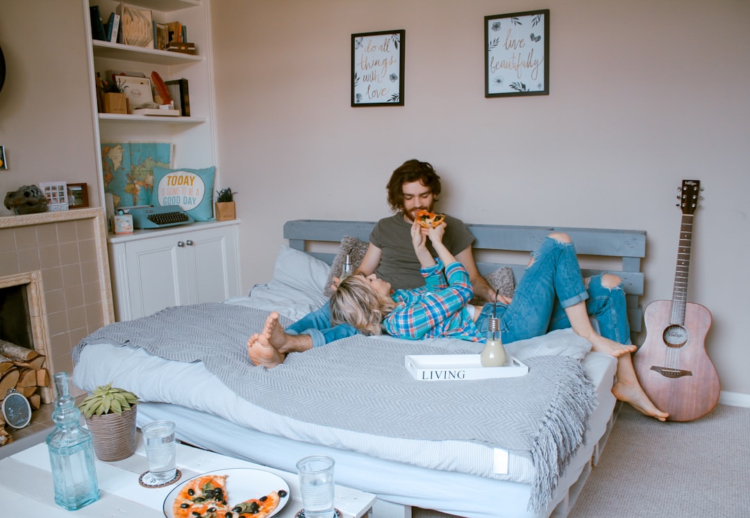 a man and woman eating pizza on a bed