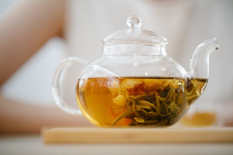 a glass teapot with a clear teacup filled with liquid