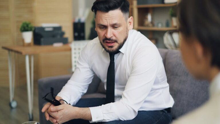 a man sitting on a couch looking at a cell phone