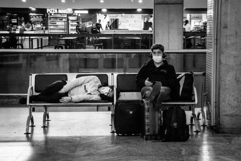 a man wearing a mask sitting on a bench with luggage