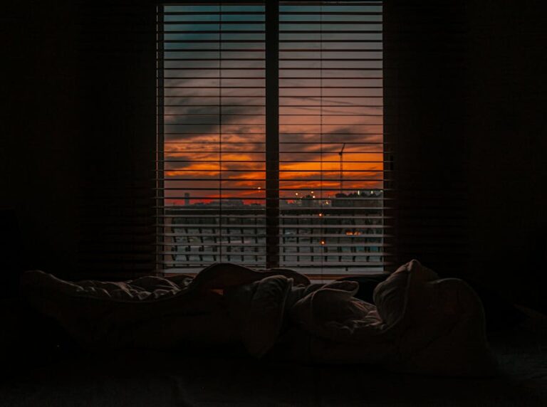 a window with blinds and a sunset