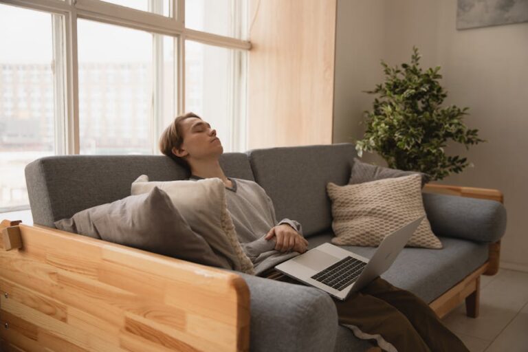 a man sleeping on a couch with his laptop