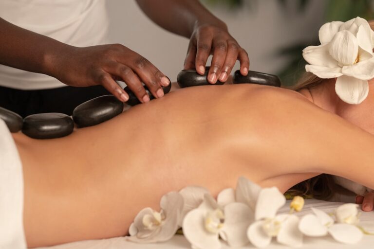 a person receiving a massage with black stones on their back