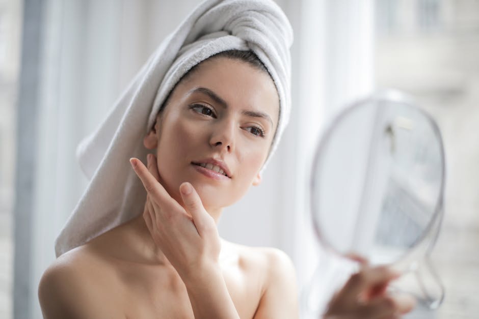 a woman with a towel on her head looking at a mirror