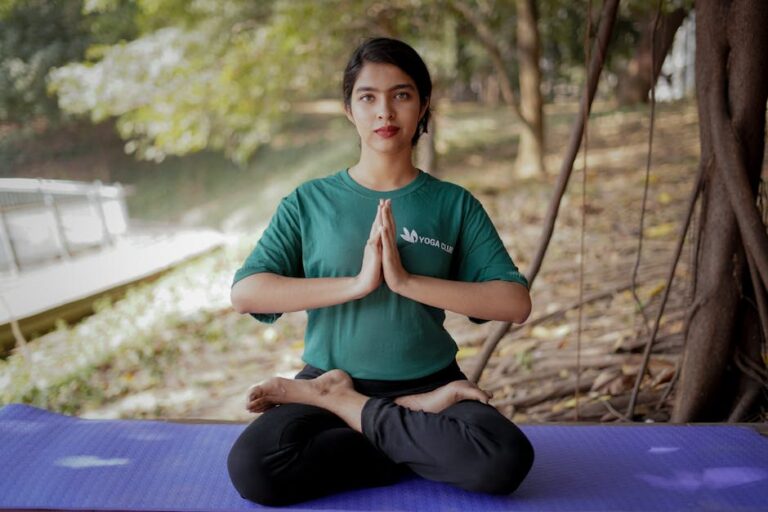 a woman sitting on a yoga mat with her hands together