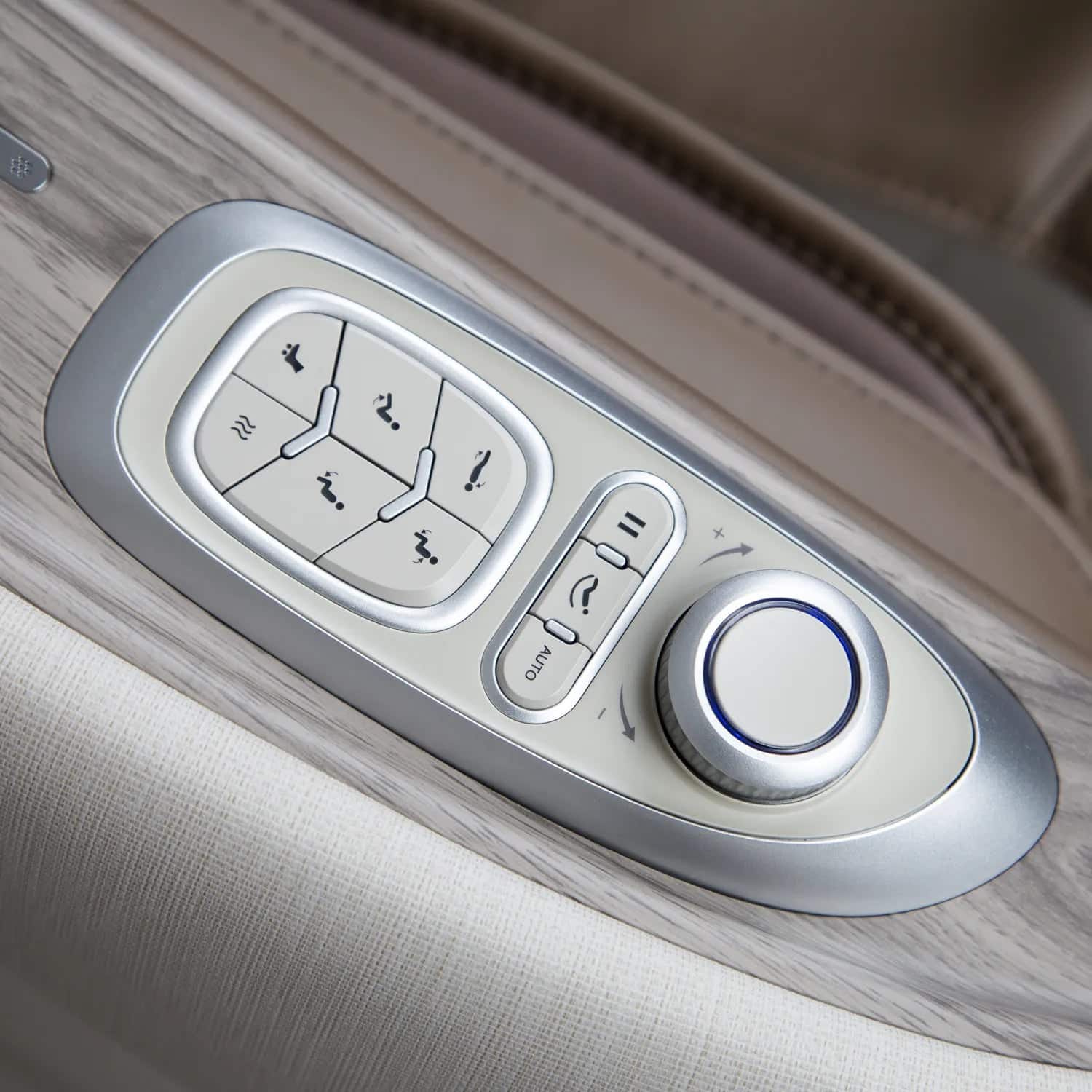 Adjustable bed remote control with light gray buttons and a silver rotary knob on a wood-grain panel