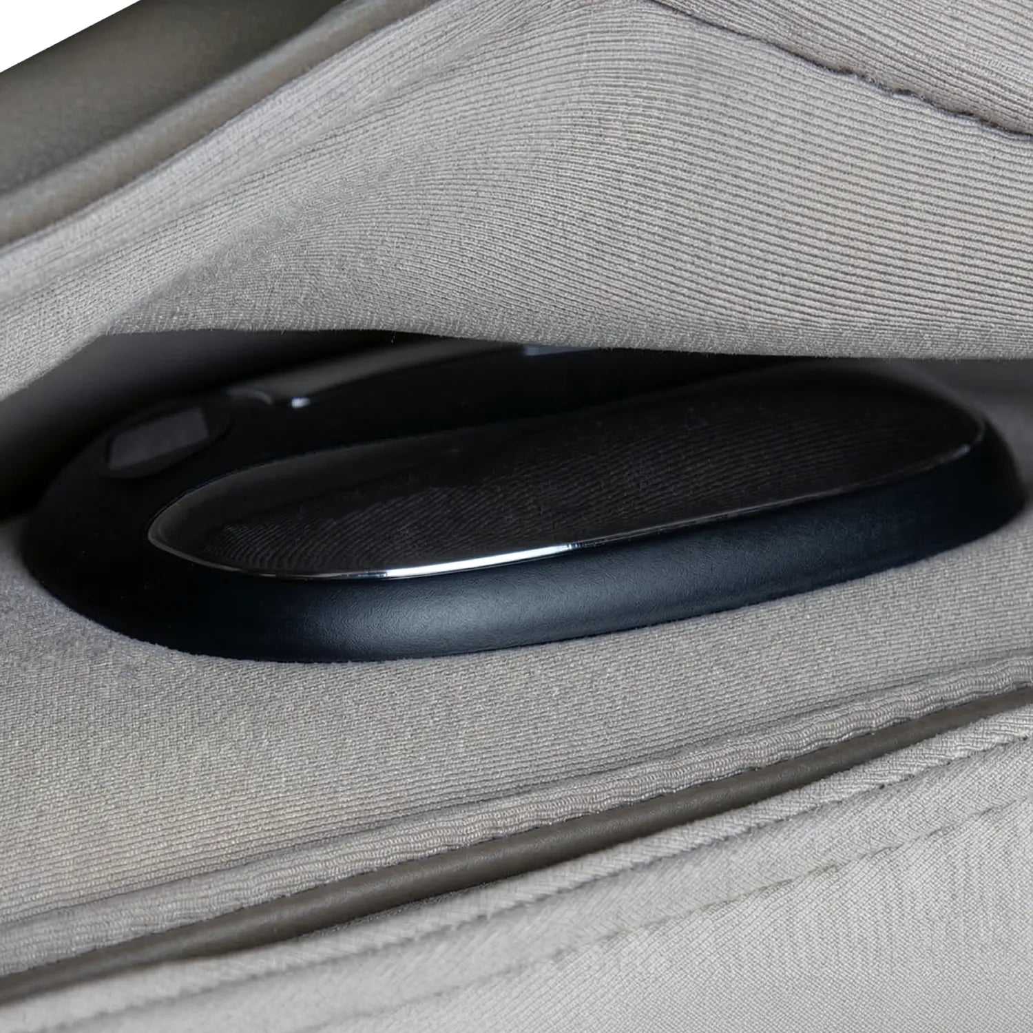 A black biometric sensor device tucked within the folds of a taupe fabric mattress cover
