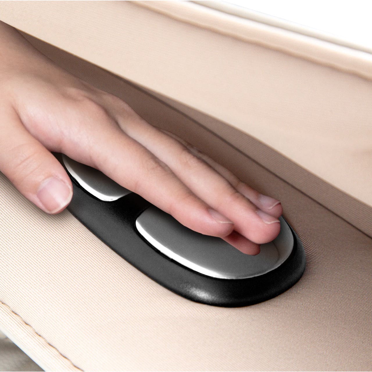 Hand operating the black and white control panel on a light beige mattress.