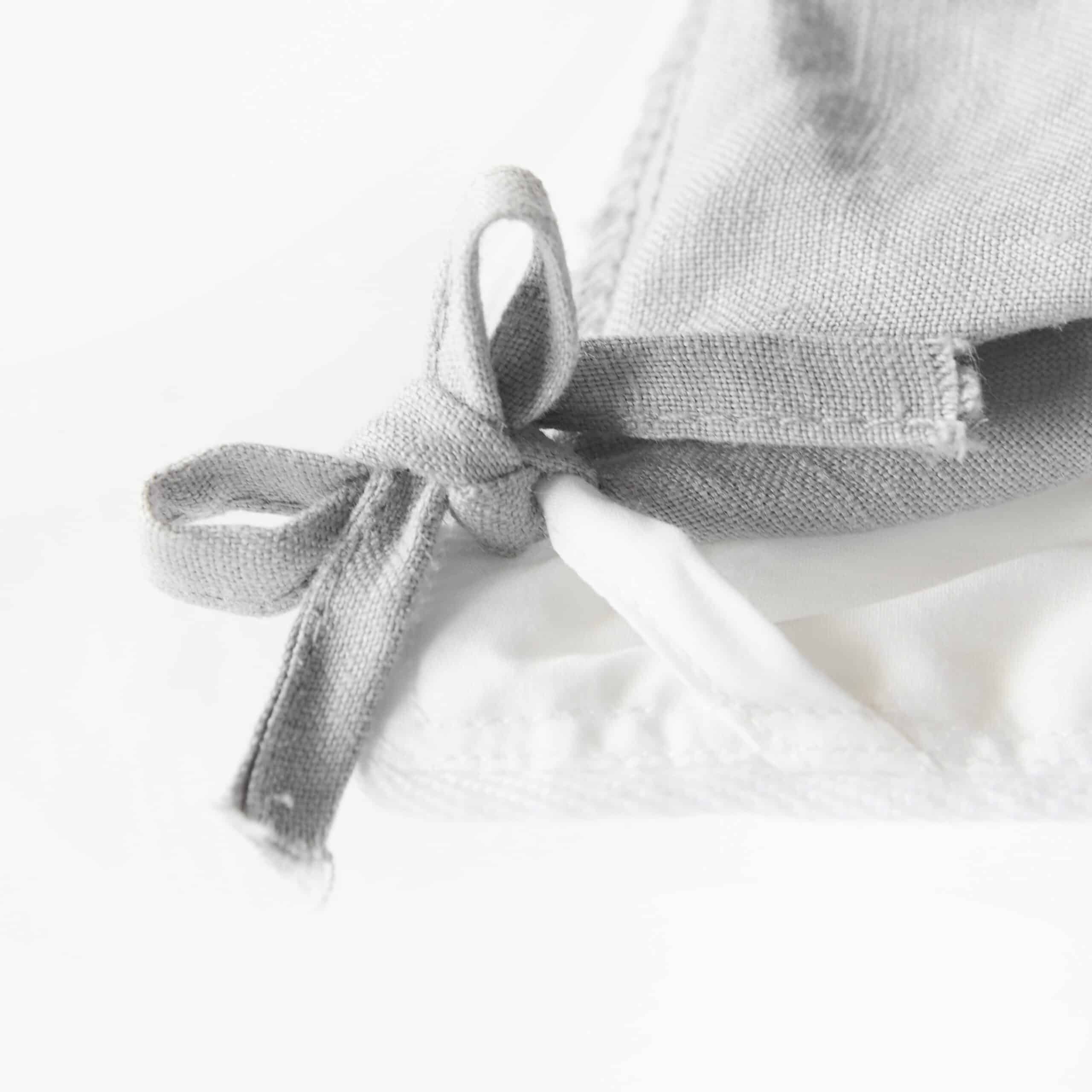 Close up of a gray organic cotton corner tie on white fabric