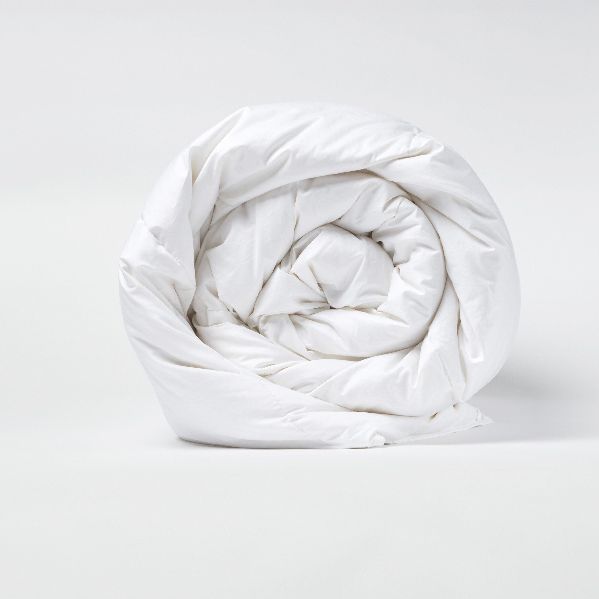 White Lightweight Comforter rolled up on a plain white surface