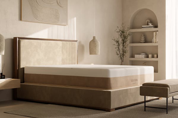 Saatva Contour 5 mattress on a bed frame in a light beige bedroom.