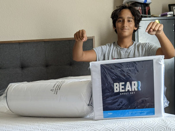 Kid proudly pointing to Bear sheet set, pillow, and mattress
