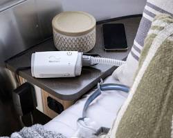 Image of ResMed AirMini CPAP machine next to a smartphone for size comparison