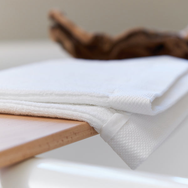 White Avocado organic cotton towel folded on a wooden surface