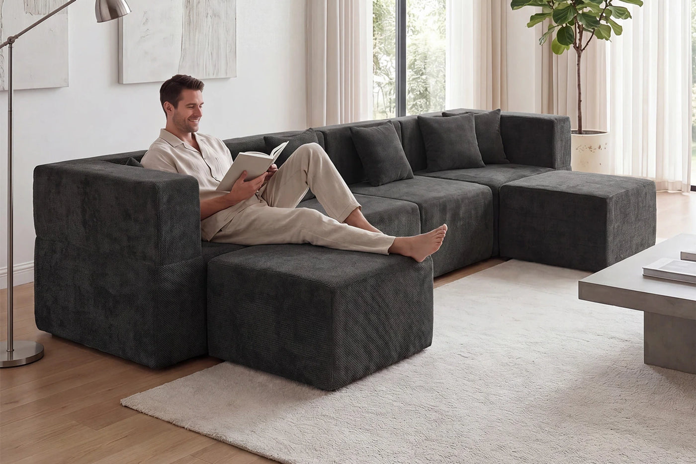 Person lounging on the chaise of a dark grey Monvane modular couch