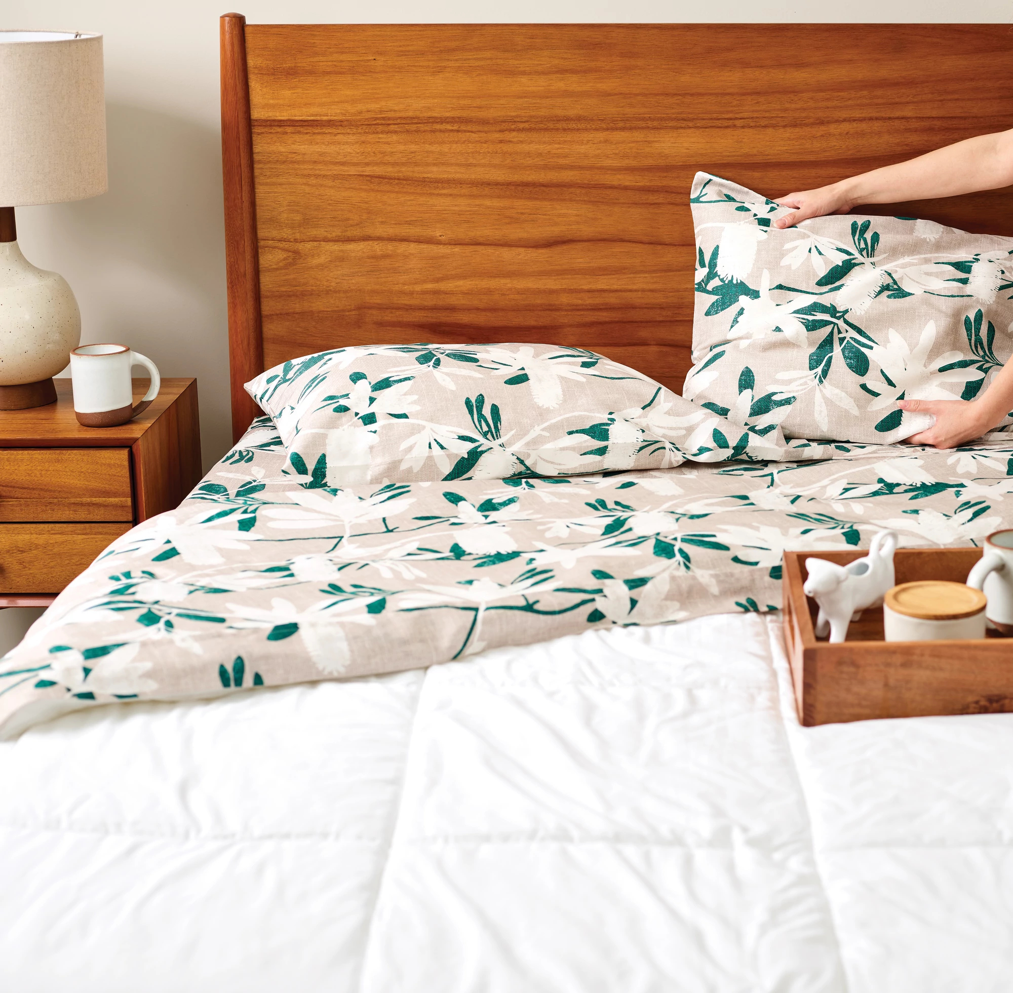 Spoonflower manufacturer photograph of a person arranging patterned sheets on a bed