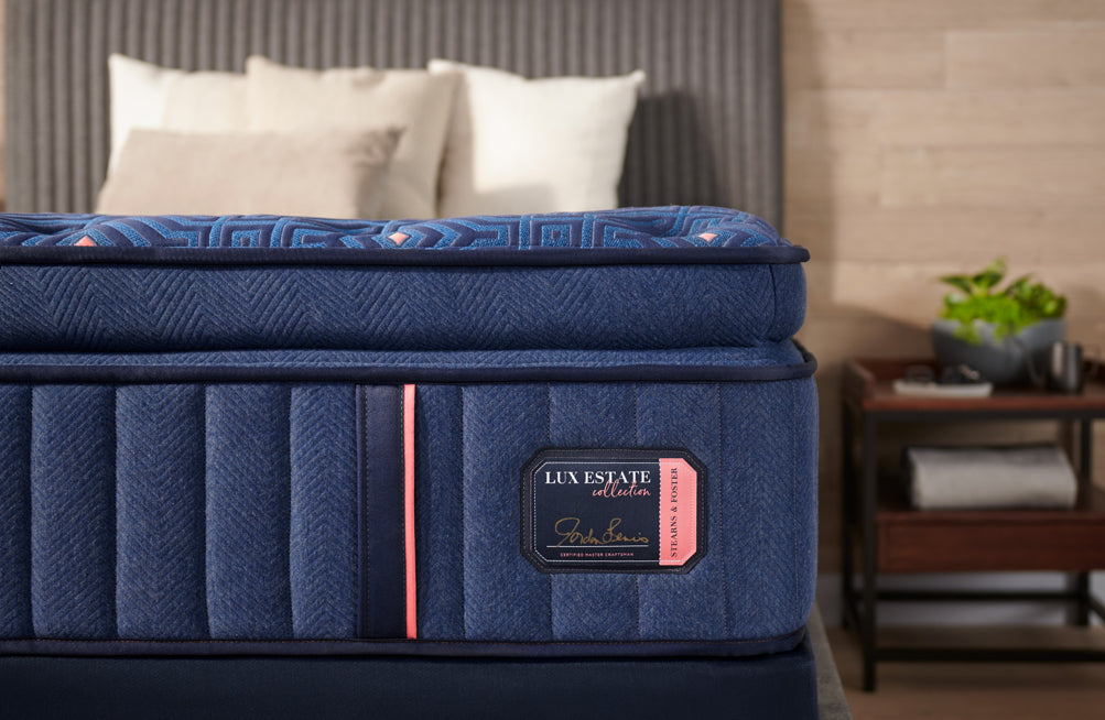 Close up of Stearns and Foster Lux Estate pillow-top construction with blue textile upholstery and collection label