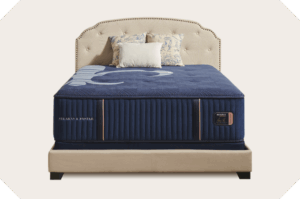 Stearns & Foster Reserve luxury mattress with navy hand-tufted quilt on an upholstered bed frame.