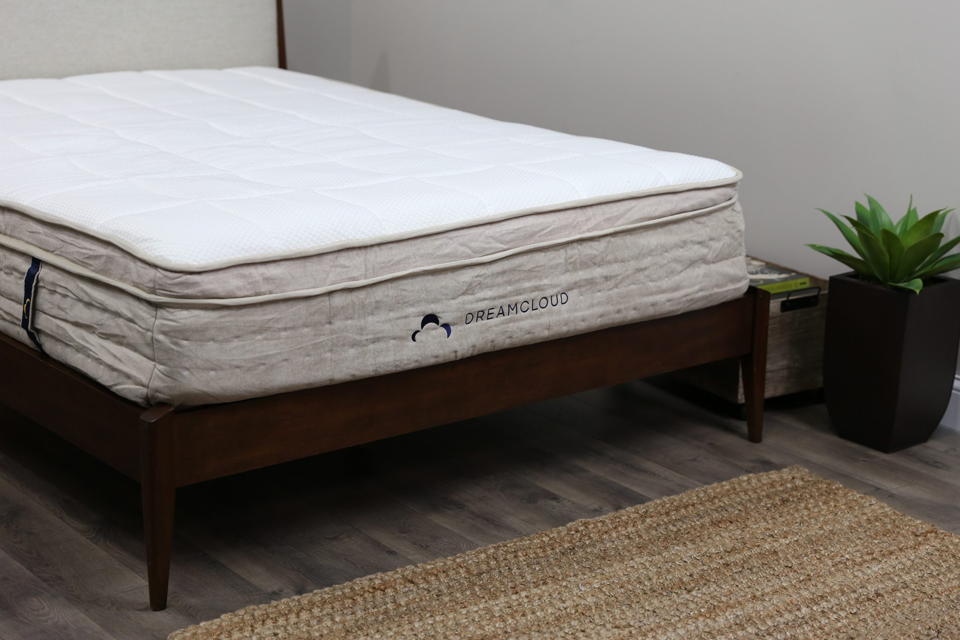 Original Yawnder photograph of DreamCloud mattress on a wooden bed frame showing the quilted top and side logo