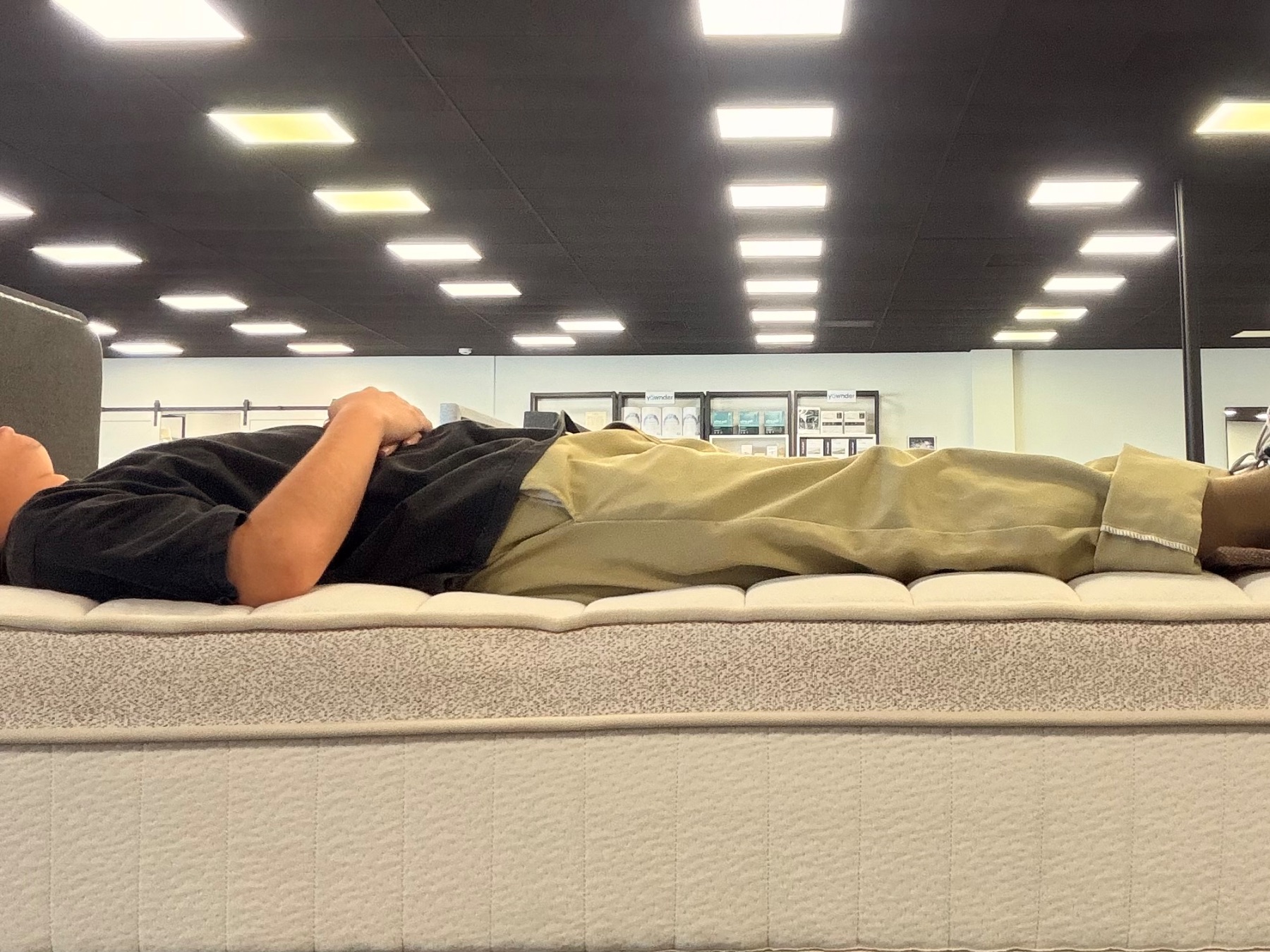 Tester lying flat on the edge of a mattress to test edge support.