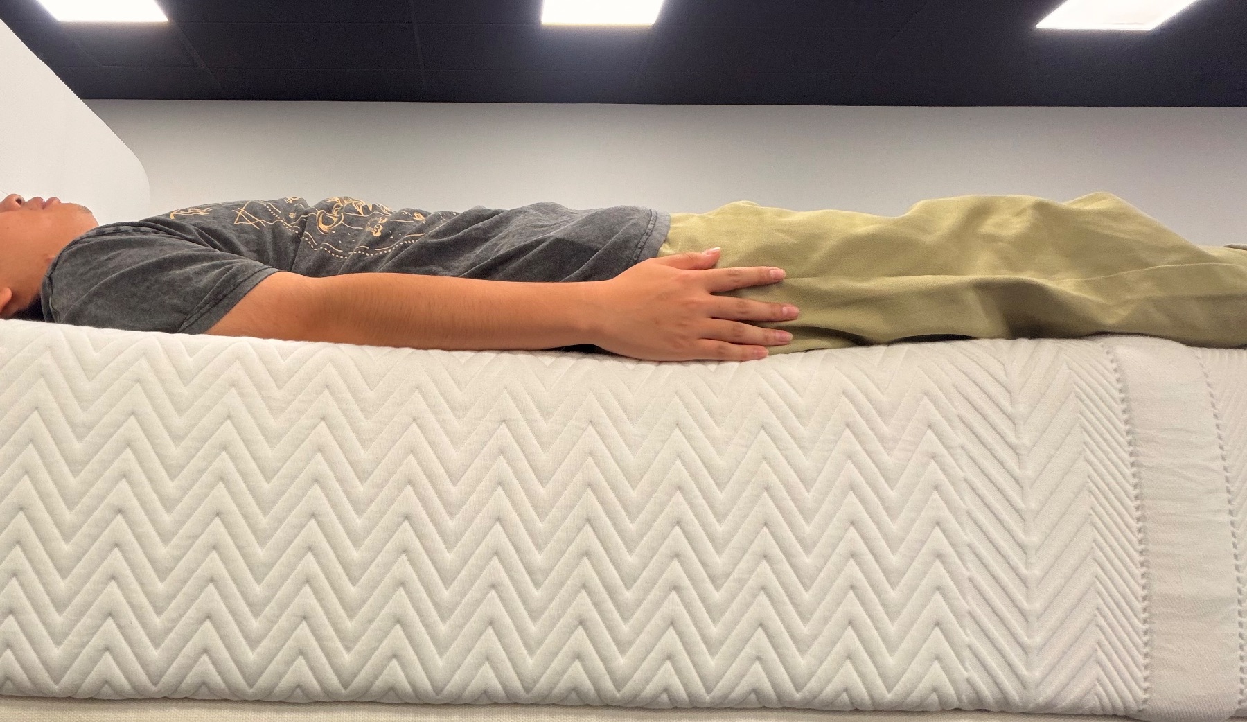 Tester lying flat right at the edge of the mattress to evaluate perimeter firmness and sinkage.
