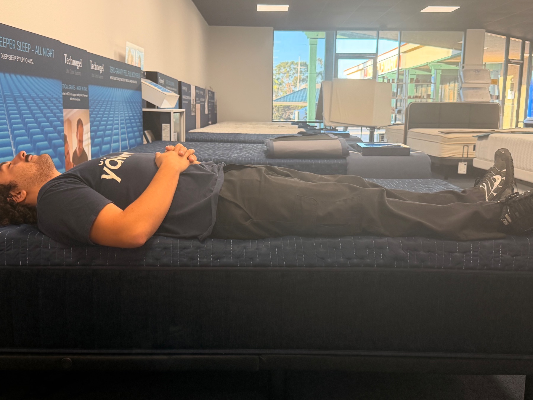 Tester lying flat along the edge of the Technogel Pro Foam mattress to test perimeter support.