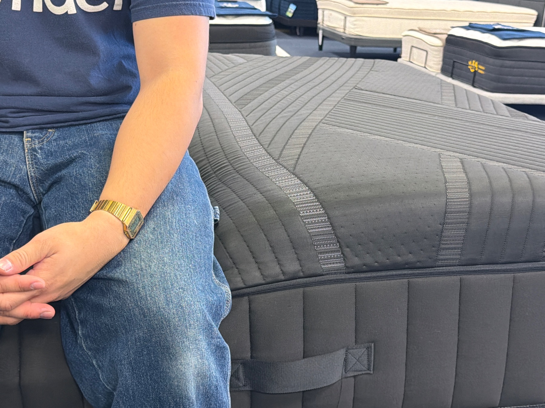 Tester sitting on the perimeter of the Black Diamond Lux Hybrid (Firm) for an edge support demonstration.