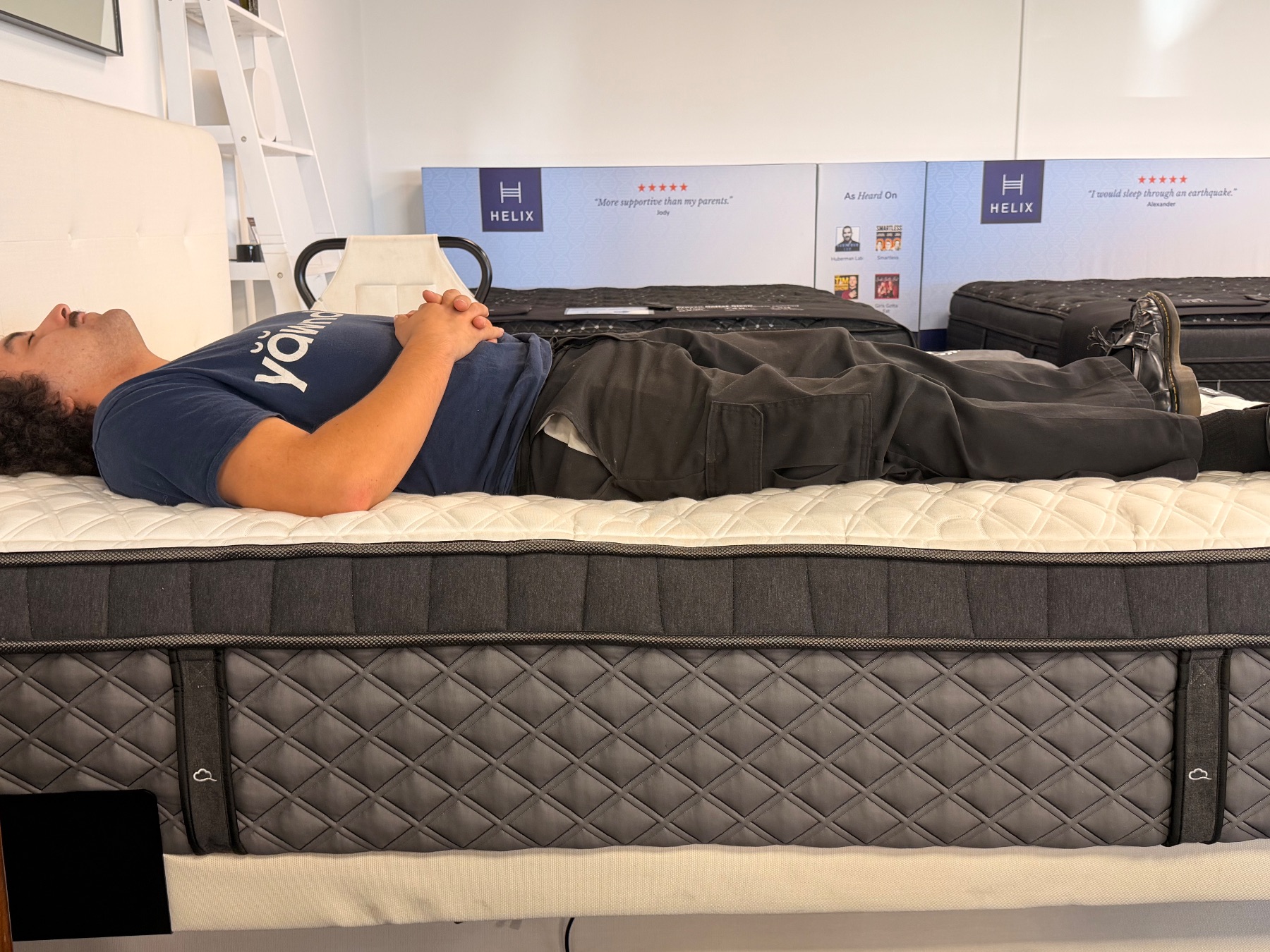 Tester lying flat along the outer perimeter of a mattress to evaluate edge sinkage.